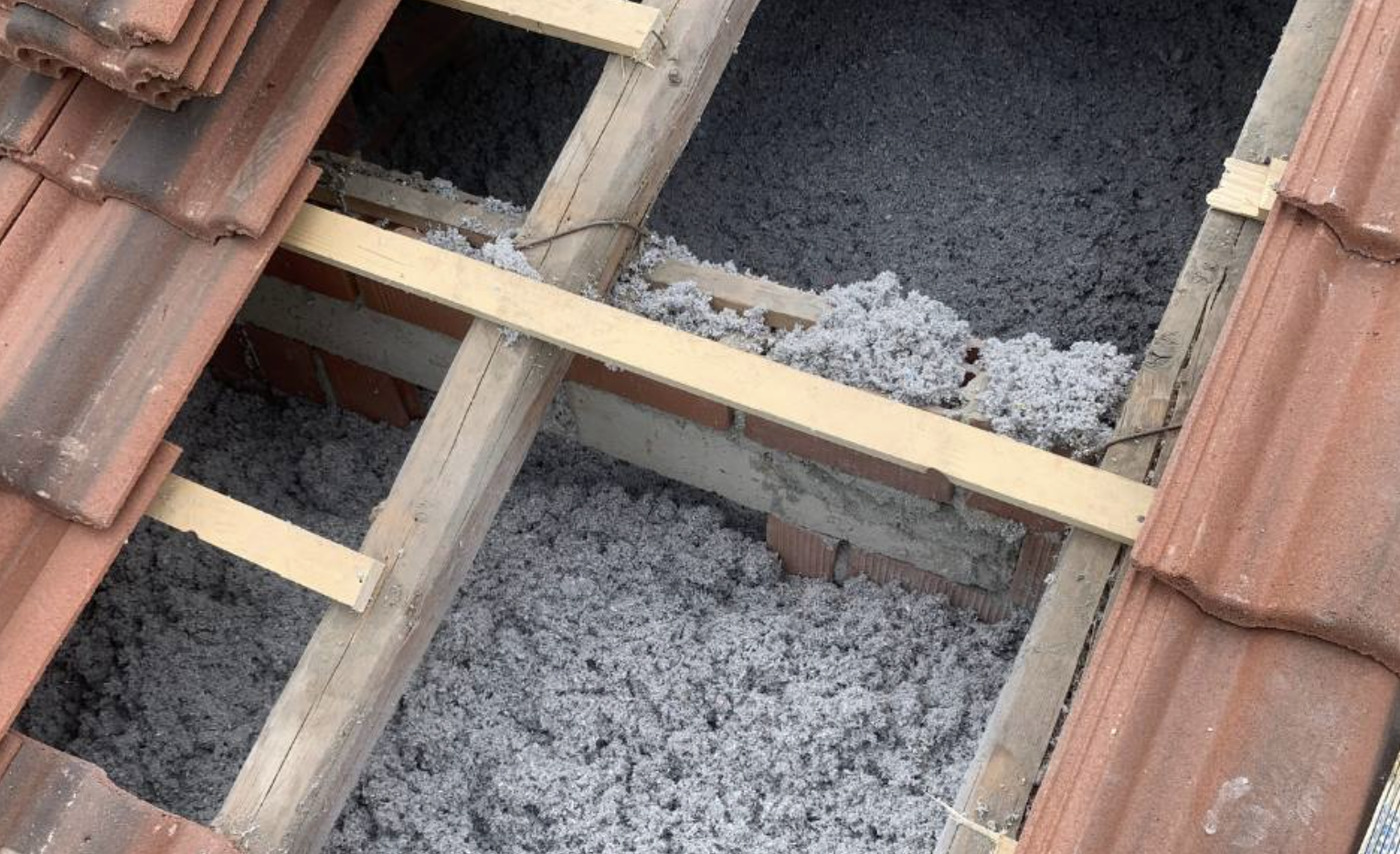 Cellulosa riciclata insufflata tra le tegole di un tetto inclinato a Verona